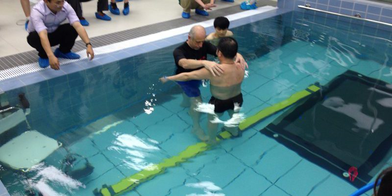 Therapist with individual in pool with obstacle course