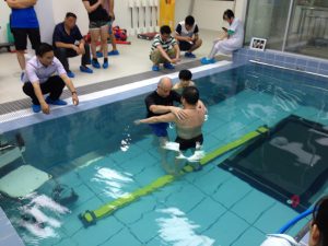 Therapist with individual in pool with obstacle course